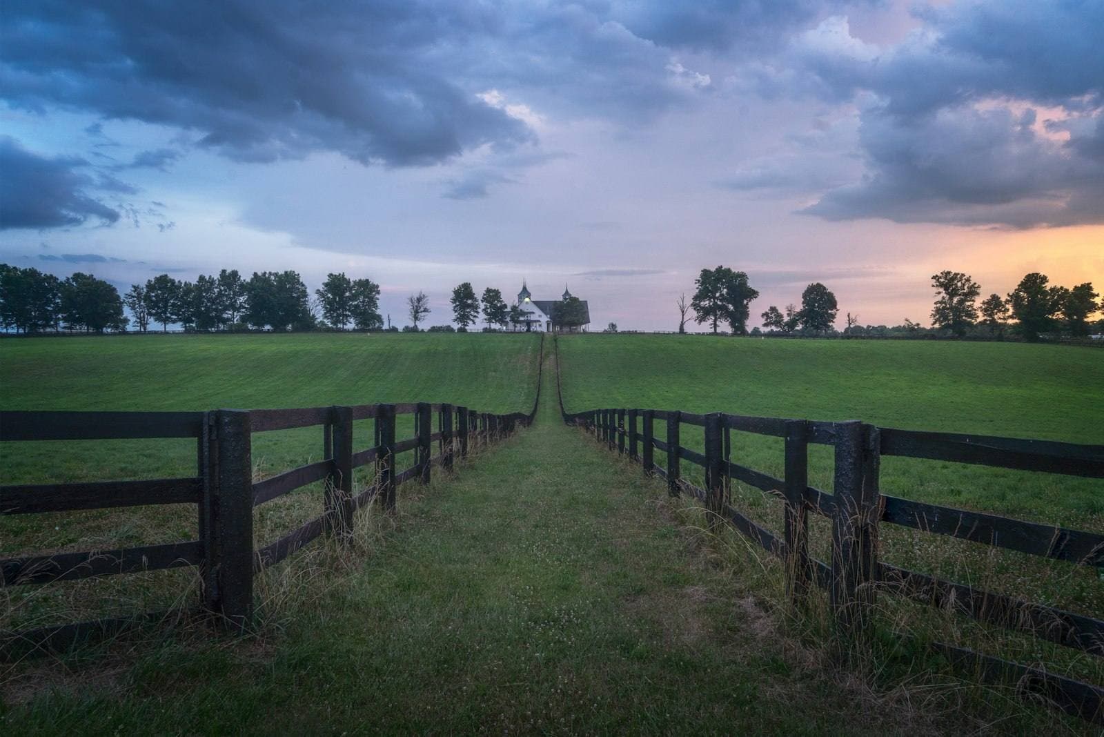 Kentucky horse-country fence line with home beyond