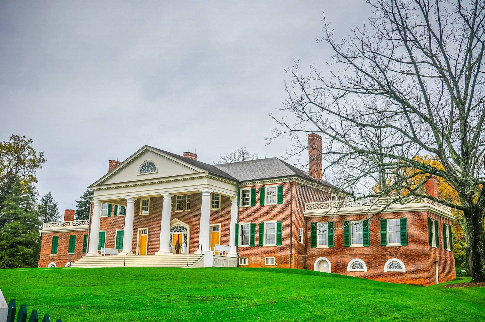 Red brick Virginia colonial on green field. Orange County appeal guide.